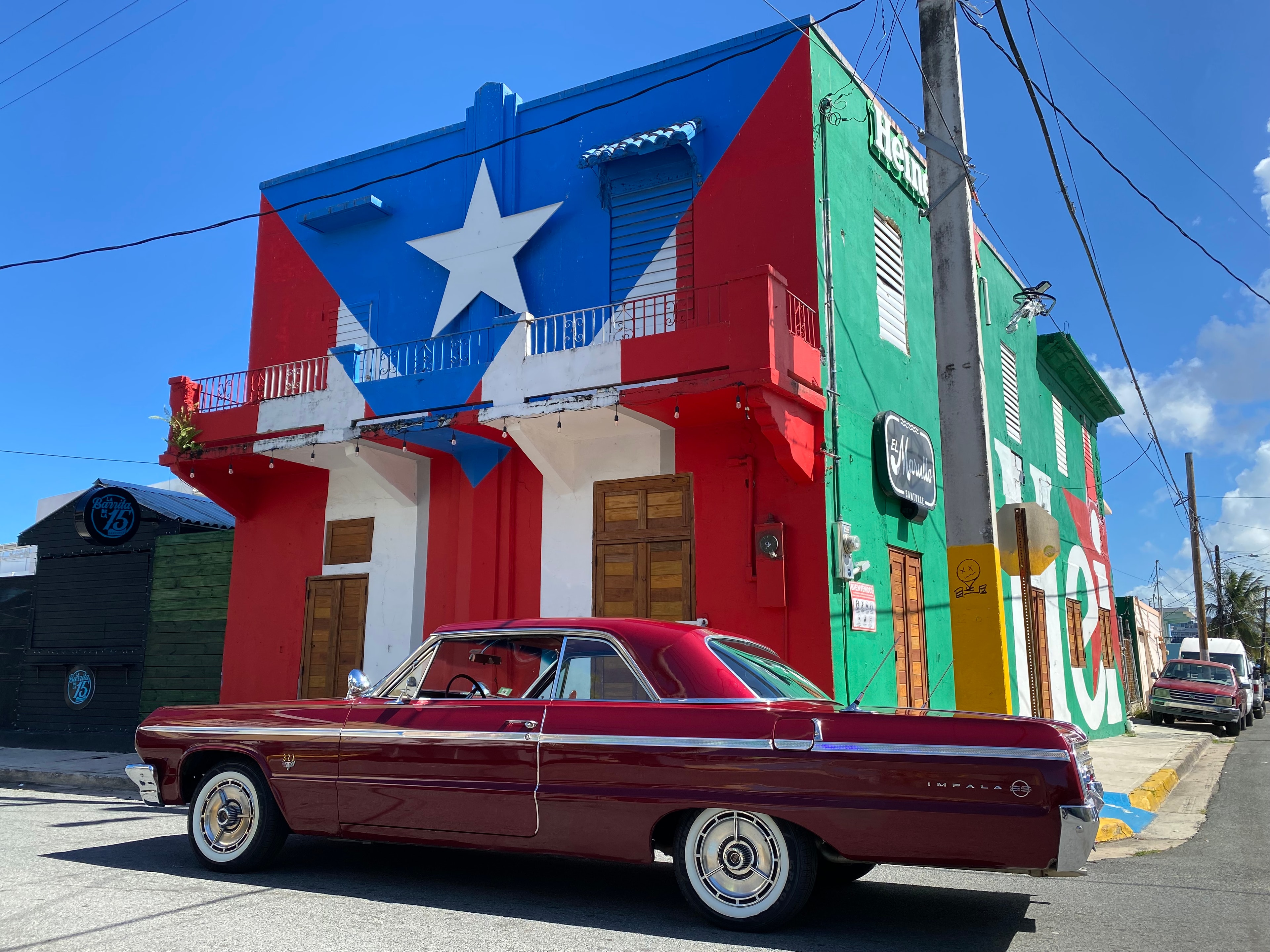 Classic Chevrolet Impala parked before a Puerto Rican flag mural